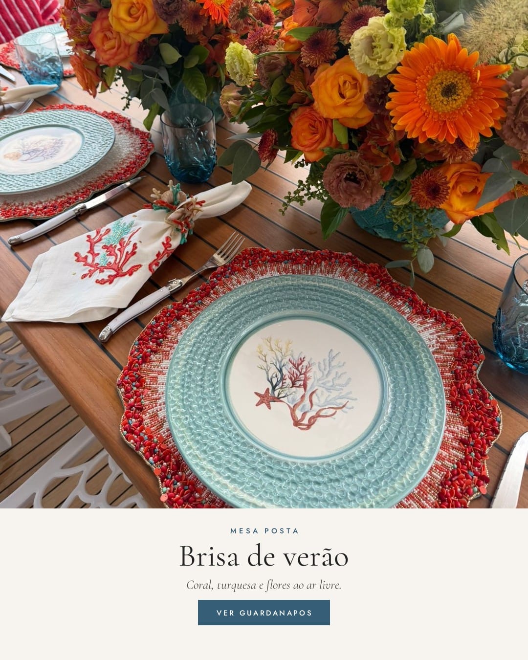 Mesa posta ao ar livre com arranjo de flores laranja, guardanapos bordados com coral e louça turquesa